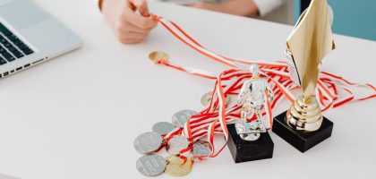 Young person displays football trophies and medals on a desk, showcasing athletic pride.