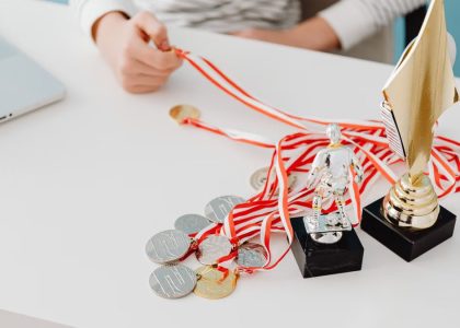 Young person displays football trophies and medals on a desk, showcasing athletic pride.